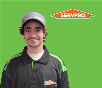 SERVPRO® employee with a hat wearing a black shirt in front of a green background