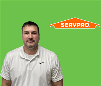 SERVPRO employee with dark hair wearing a white shirt in front of a green background