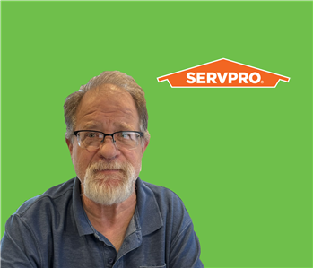 SERVPRO employee with light hair wearing a shirt in front of a green background