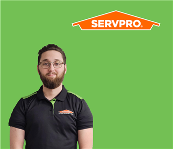 SERVPRO employee with dark hair wearing a black shirt in front of a green background