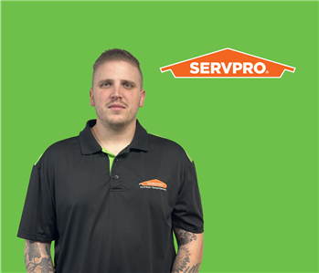 SERVPRO employee with dark hair wearing a black shirt in front of a green background