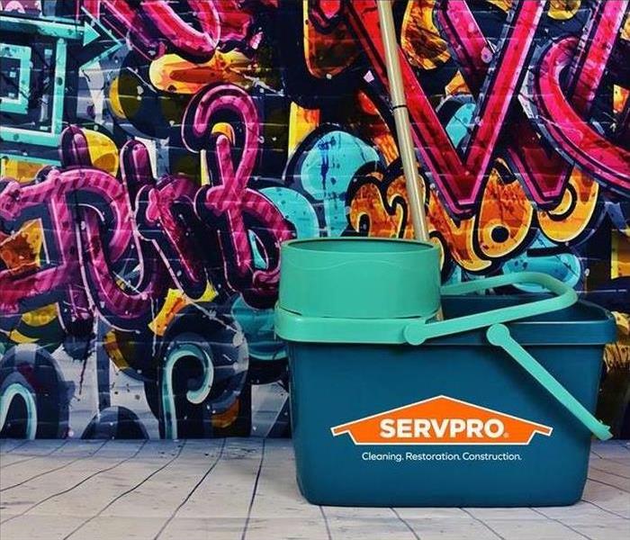 mop bucket with servpro logo in front of wall of graffiti